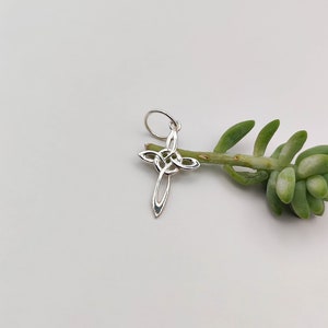 May include: Silver Celtic knot cross charm pendant. The cross is intricately designed with a knot pattern and has a loop at the top for attaching to a chain or bracelet.