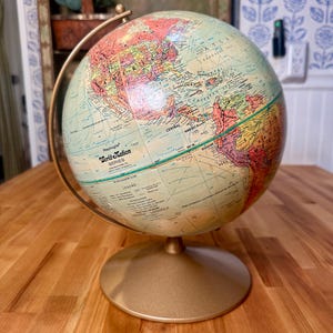 May include: A vintage Replogle World Nation Series globe with a gold-colored base and meridian. The globe features a detailed map with various countries and continents in shades of green, red, and yellow. The globe is a classic educational and decorative item.