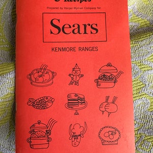 May include: A red booklet with the title "Oven Cooking Guide & Recipes" and the logo "Sears Kenmore Ranges". The cover features illustrations of various foods, including a fish, a cake, and a pie.