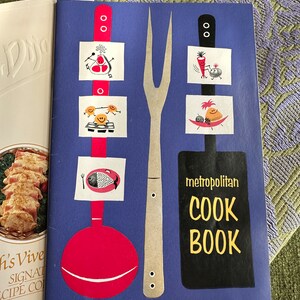 May include: A blue cookbook with the title "Metropolitan Cook Book" in yellow letters. The cover features illustrations of a fork, a ladle, and various food items.