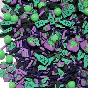 May include: A collection of polymer clay embellishments in a variety of shapes and colors. The assortment includes green poison bottles with an "X" and skull design, purple poison bottles, black bats, green spheres, and purple rods.