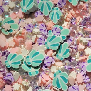 May include: A mix of colorful resin charms, including seashells, flowers, and beads. The charms are in shades of pink, purple, white, and teal.