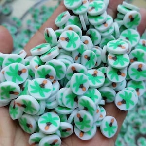 May include: A large quantity of small, white, round, flat, resin palm tree embellishments. The palm trees are green with brown trunks.