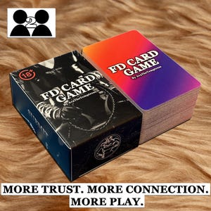 Könnte beinhalten: Zwei Kartenspiele, eines in einer schwarzen Box und das andere mit einem Farbverlauf von Rot nach Lila. Auf der Box steht "FD CARD GAME" mit dem Text "MORE TRUST. MORE CONNECTION. MORE PLAY."