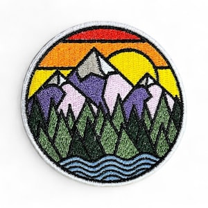 May include: Round embroidered patch featuring a mountain landscape with a sunset. The design includes purple mountains, green trees, and a blue river, all set against a yellow, orange, and red sky. The patch has a white border.