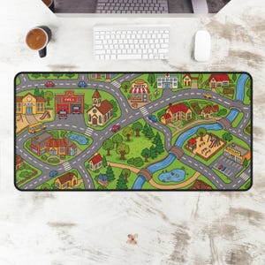 May include: A colorful, rectangular desk mat featuring a town map design. The mat includes roads, buildings like a school, fire station, church, and bakery, and a river with bridges. Cars, trees, and a playground are also depicted.