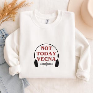 May include: White sweatshirt with the text "NOT TODAY VECNA" in burgundy, framed by a black headphone design. Below the text is a sound wave graphic. The sweatshirt is a Gildan brand.