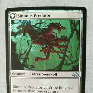 Op de afbeelding: Een groene en bruine fantasy-illustratie van een wezen genaamd "Sinuous Predator". Het wezen is een Eldrazi-weerwolf met meerdere koppen met een kracht en uithoudingsvermogen van 4/4. De tekst luidt: "Sinuous Predator kan niet door meer dan één wezen geblokkeerd worden. Een ander soort transformatie heeft plaatsgevonden."