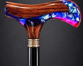 May include: A walking cane featuring a polished dark wood shaft and a handle crafted from wood and translucent blue and pink resin. The handle is inlaid with iridescent shell fragments and features a gold-toned metal collar with a Celtic knot pattern.