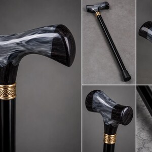 May include: A walking cane featuring a black shaft and a T-shaped handle with a marbled black and white pattern. A gold-colored metal collar with an intricate woven design connects the handle to the shaft, which ends in a black rubber tip.