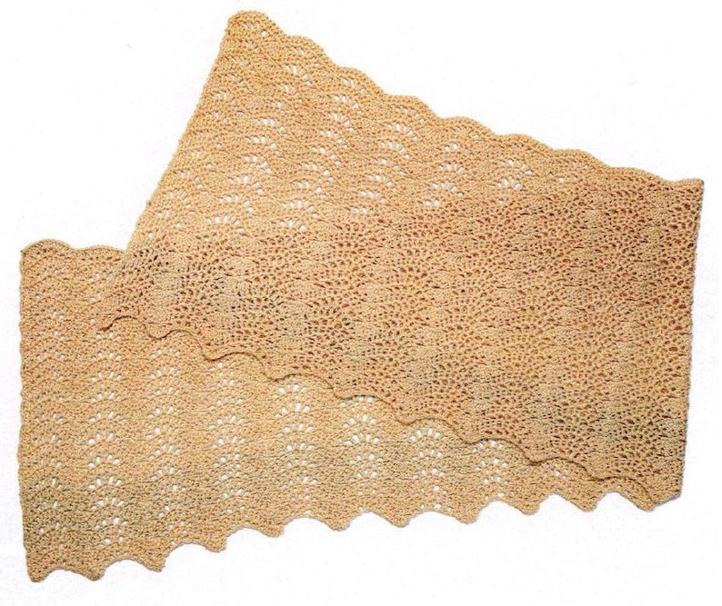 May include: A beige, crocheted shawl with a scalloped edge. The openwork design creates a delicate, airy texture. The shawl is folded, showcasing its triangular shape and intricate stitch pattern. The color is a soft, neutral tone.