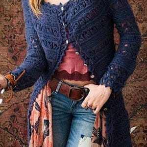 Pode incluir: Um casaco de crochê azul com uma bainha franjada e um lenço de estampa floral. O casaco tem um fecho de botões e mangas compridas.