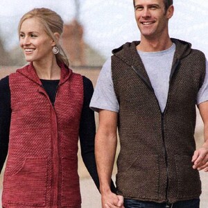 May include: A woman and a man are holding hands, both wearing hooded vests. The woman's vest is red, and the man's is brown. Both vests have a zipper closure and pockets. The woman is wearing a black long-sleeve shirt under her vest.