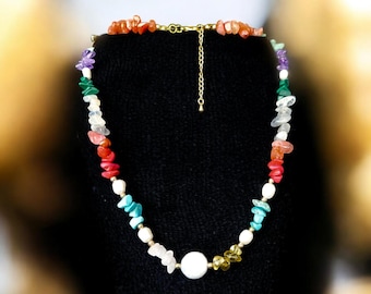 May include: A colorful gemstone necklace with a large white pearl pendant. The necklace features a variety of stones, including turquoise, red coral, and amethyst.