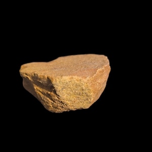 May include: A rough, irregularly shaped, brown and yellow rock with a flat top.