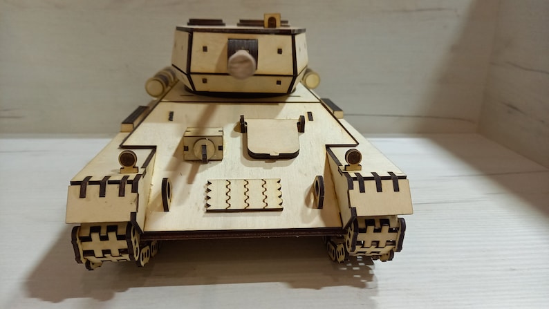 Puede incluir: Un modelo de tanque de madera, con un dise&ntilde;o detallado y un acabado marr&oacute;n. El tanque tiene una torreta con un ca&ntilde;&oacute;n y orugas en la parte inferior.