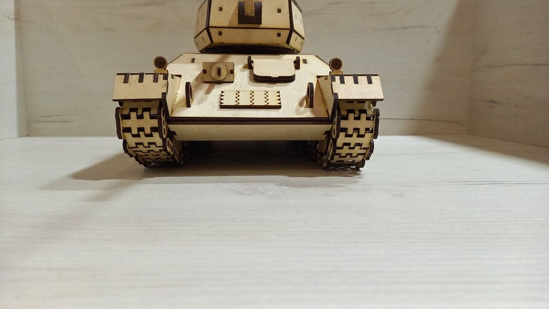 Puede incluir: Un modelo de tanque de madera, con orugas detalladas y una torreta. El modelo est&aacute; hecho de madera marr&oacute;n claro y tiene un dise&ntilde;o realista.