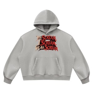 Puede incluir: Una sudadera con capucha de color gris claro que presenta un bolsillo tipo canguro frontal y un estampado gráfico en el pecho. El texto "YOU SCREAM, I SCREAM, WE ALL SCREAM" aparece en una fuente estilizada de color rojo y oro metálico.