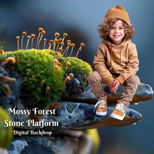May include: A young child wearing a brown hoodie and a brown beanie sits on a mossy stone platform. The platform is covered in green moss and small orange mushrooms. The background is a blurred blue.