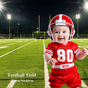 May include: A baby wearing a red football uniform with the number 80 on the front, standing on a green football field with white lines. The baby is wearing a red helmet and smiling.