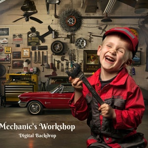 May include: A young boy dressed in a red and grey mechanic's jumpsuit smiles while holding a wrench in a garage setting. The garage is decorated with tools, signs, and a red car.