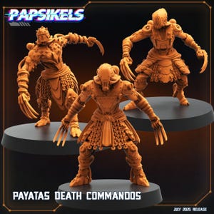 May include: Three orange-colored miniature figures of armored warriors with claw-like hands. The figures are standing on black circular bases. The text "PAYATAS DEATH COMMANDOS" is displayed at the bottom of the image, with the "PAPSIKELS" logo at the top.