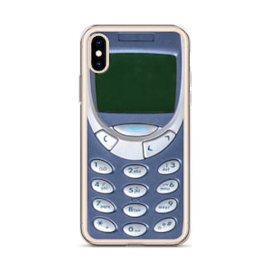 Puede incluir: Una funda de teléfono transparente con un diseño de teléfono móvil vintage. El teléfono es azul y plateado con una pantalla negra y un teclado con números y letras.