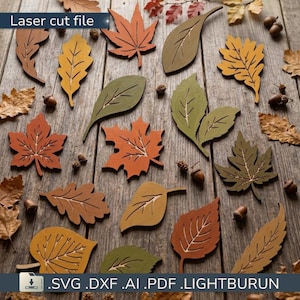 Peut inclure: Une collection de feuilles en bois découpées au laser dans diverses couleurs d'automne, notamment orange, jaune, marron et vert olive. L'ensemble présente des formes de feuilles d'érable, de chêne et de bouleau avec des nervures gravées.