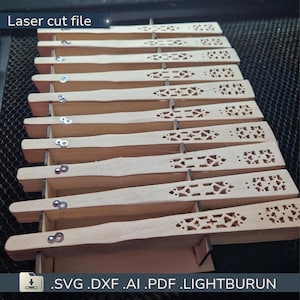 Peut inclure: Ensemble de ventilateurs en bois découpés au laser, chacun avec un motif géométrique décoratif. Les éventails sont de couleur marron clair et présentés dans un support en bois. Le texte "Laser cut file" est visible.