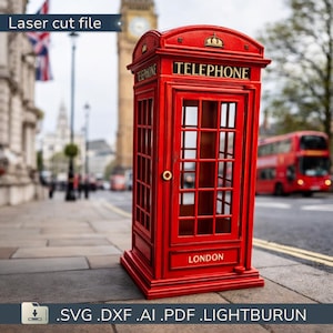 May include: A miniature red telephone box with the word "TELEPHONE" in gold lettering. The box has a glass door and windows, and the word "LONDON" is printed at the bottom. The background features a street scene with a double-decker bus and Big Ben.