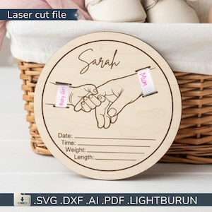 Peut inclure: Un fichier de découpe laser en bois rond avec le nom "Sarah" en cursive. Le design présente une main de parent tenant la main d'un bébé, avec des rubans "Baby Girl" et "Mum". Comprend un espace pour la date, l'heure, le poids et la longueur. Le texte "Laser cut file" est en haut.