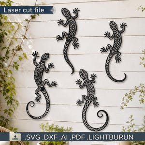 May include: Four black metal lizard wall art pieces with intricate tribal patterns are mounted on a white wooden wall. The lizards have curled tails and are in various poses. The top left corner has the text "Laser cut file".