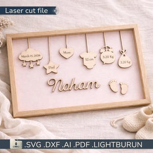 Peut inclure: Annonce de naissance encadrée en bois avec le nom "Noham" en cursive. Comprend des découpes en bois d'un nuage avec des étoiles, une étoile, un cœur, un body (52 cm), une horloge (3,20 Kg), une cigogne portant un bébé (3,20 Kg) et des empreintes de pas de bébé. Le texte "Laser cut file" est en haut.
