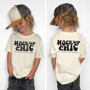 Puede incluir: Un niño con una camiseta de color crema con el texto "MOCKUP CHIC" en negro y una gorra de béisbol marrón y gris. La camiseta también tiene el texto "REAL MODELS & REAL APPAREL" en negro.