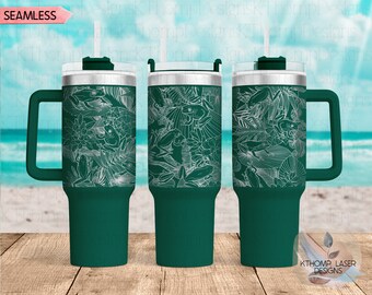 May include: A green stainless steel tumbler with a white design of frogs and tropical leaves. The tumbler has a lid and a handle. The tumbler is on a wooden surface.