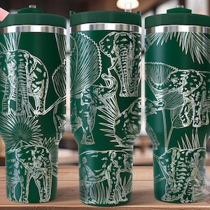 Peut inclure: Un gobelet en acier inoxydable vert avec un motif d'éléphant blanc et de feuilles tropicales. Le gobelet a un couvercle et une poignée. Le texte "SEAMLESS" est visible dans le coin supérieur gauche de l'image.