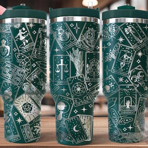 May include: A green stainless steel tumbler with a handle and a white design of tarot cards. The tumbler is seamless and has a lid.