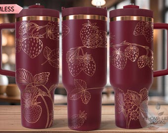 May include: Burgundy insulated tumbler with a gold strawberry design. The tumbler has a handle, a lid, and a straw. The design features strawberries, leaves, and flowers. The word "SEAMLESS" is in a pink banner.