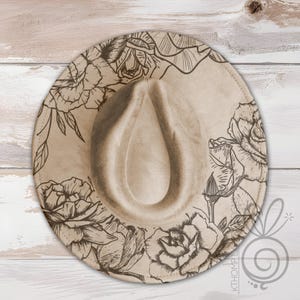 May include: A beige fedora hat with a floral design. The hat features a wide brim and a teardrop-shaped crown. The floral design is a series of roses and leaves in a dark brown color, creating a contrast against the hat's neutral tone.