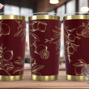 May include: Three stainless steel tumblers with a gold rim and a burgundy base. The tumblers feature a gold outline of lemons and leaves on a burgundy background. The text "SEAMLESS" is visible in the top left corner of the image.