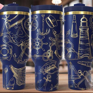 May include: A blue stainless steel tumbler with a gold nautical themed design. The tumbler has a lid and a handle. The design includes anchors, a lighthouse, a compass, a ship's wheel, and a nautical map.