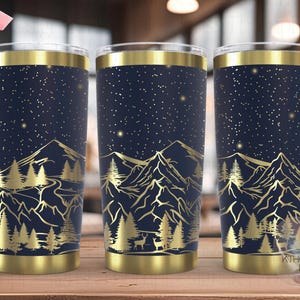 May include: Three stainless steel tumblers with a gold rim and a design of a mountain range with trees and stars on a dark blue background. The tumblers are seamless.