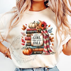 May include: A white t-shirt with a graphic design of a stack of books, a pumpkin, and fall foliage. The text on the graphic says "Just a girl who loves fall".