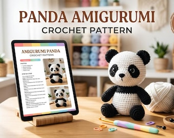 May include: A digital crochet pattern for a panda amigurumi displayed on a tablet, featuring a finished white and black crocheted panda toy, balls of yarn, a colorful crochet hook, and small plastic eyes on a wooden table surface.