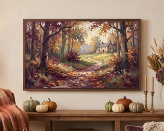 May include: A rectangular landscape painting in a dark wood frame depicting an autumn forest path leading to a small cottage. The scene features warm tones of orange, brown, and yellow foliage, with dark tree trunks and a soft, light-filled sky.