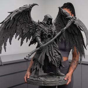 May include: A detailed gray sculpture of a hooded figure with large feathered wings, holding a scythe. The figure is standing on a stone base. The sculpture has intricate details and a gothic aesthetic.