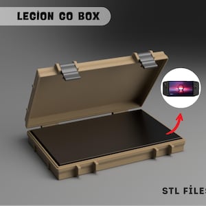 Puede incluir: Estuche rectangular beige con tapa con bisagras y cierres metálicos plateados. El estuche está abierto, revelando un interior negro. El texto "LEGION GO BOX" está en la parte superior y "STL FILES" en la inferior. Una pequeña imagen de un dispositivo de juego portátil está en la parte superior derecha.