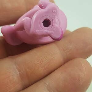 May include: A close-up of a pink plastic toy pony figurine. The underside of the toy is visible, showing a hexagonal hole and the text "&copy; 2009 Hasbro" and "China C-031G".
