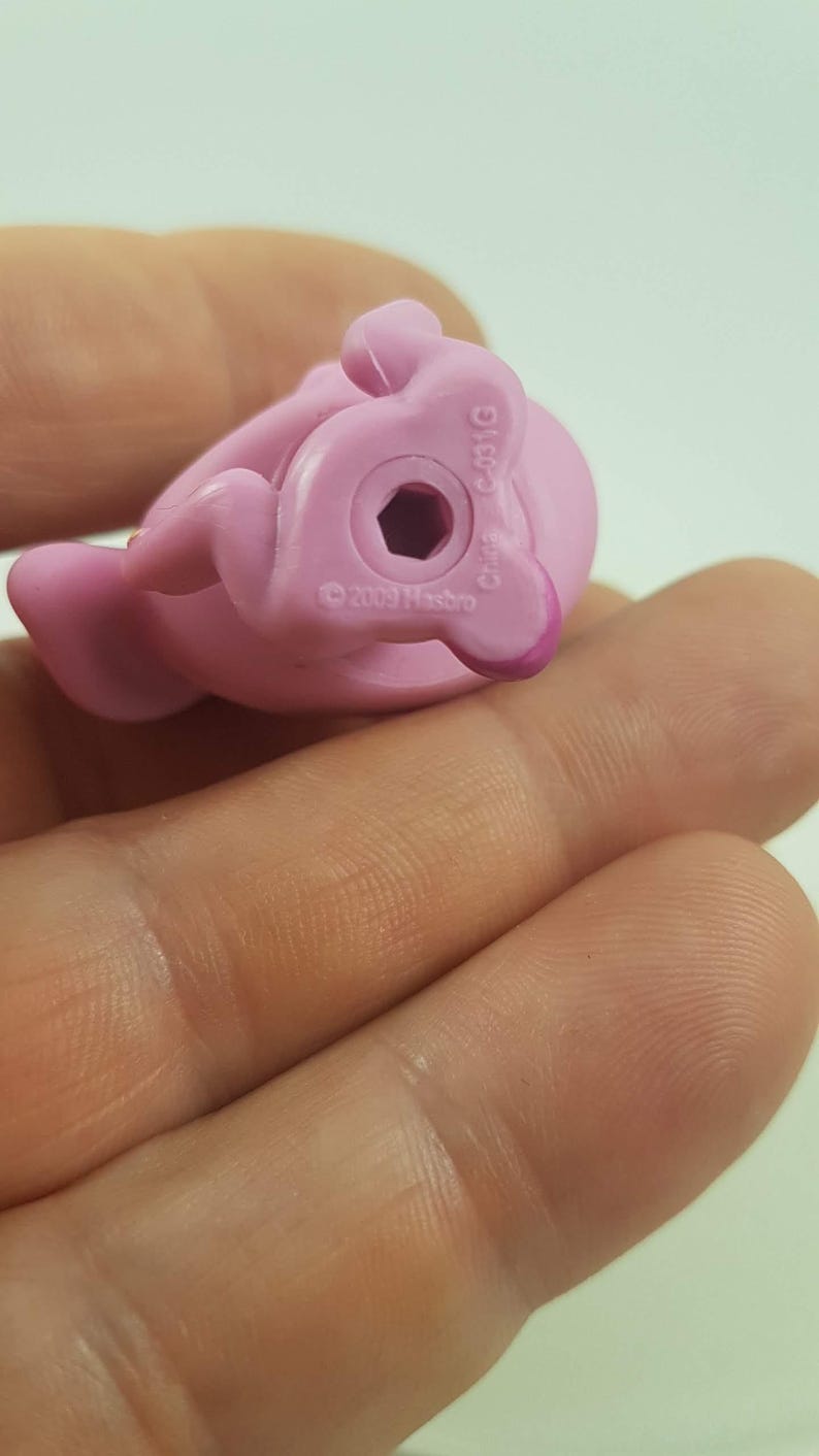 May include: A close-up of a pink plastic toy pony figurine. The underside of the toy is visible, showing a hexagonal hole and the text "&copy; 2009 Hasbro" and "China C-031G".