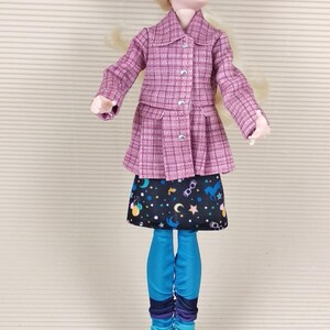 May include: A doll wearing a pink plaid shirt, a black skirt with a celestial print, blue leggings, and pink boots.